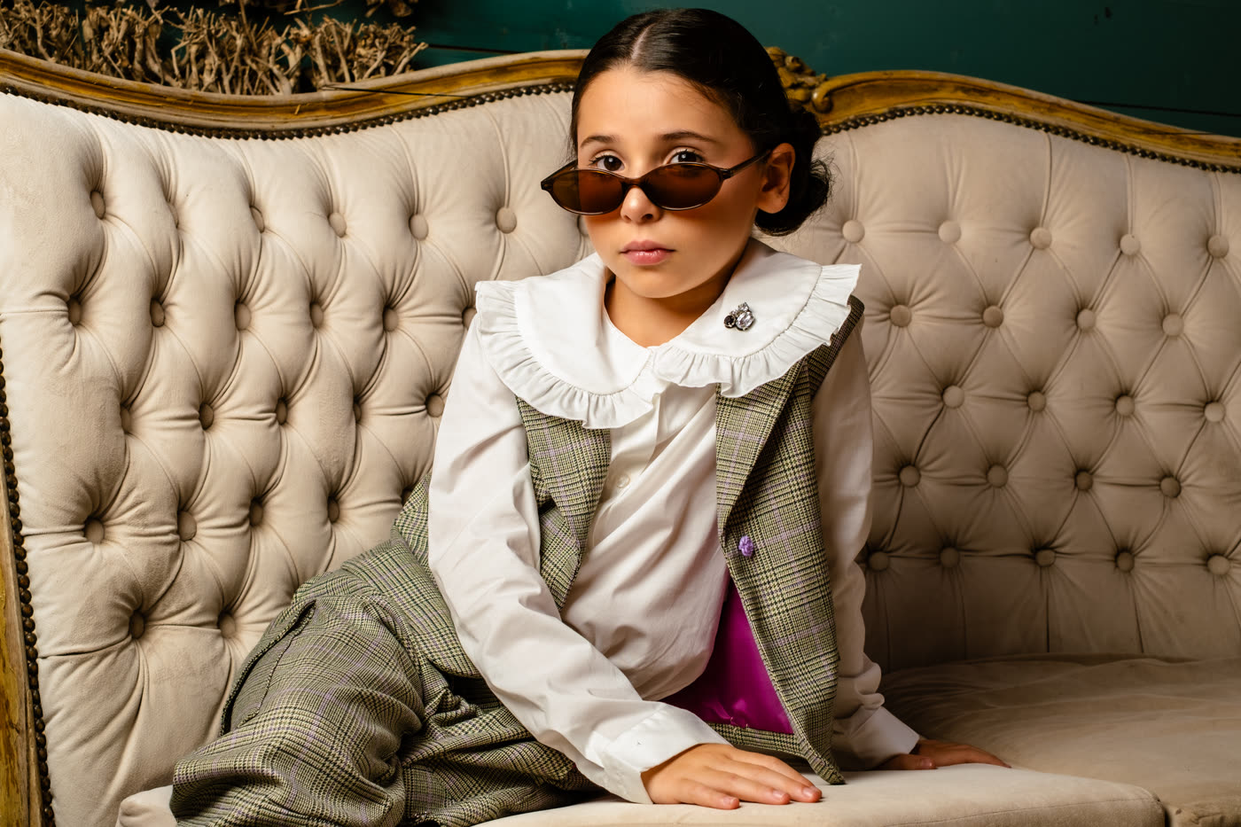 Ritratto editoriale di una bambina in completo sartoriale Illiana su un divano vintage