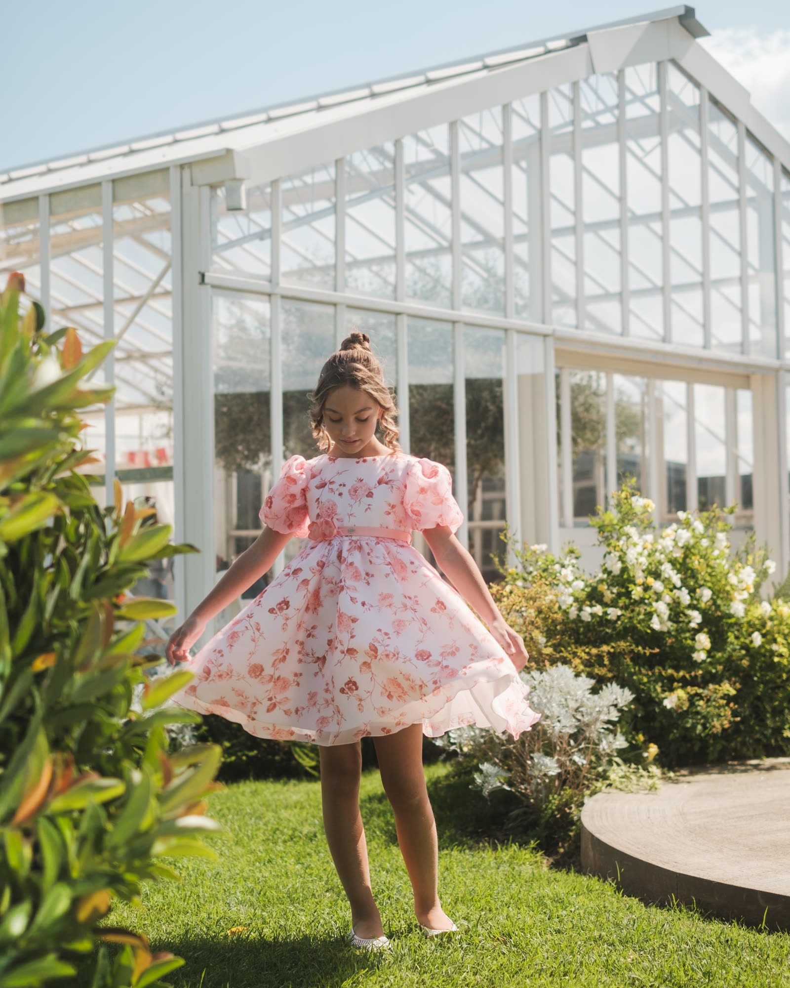 Bambina con abito floreale Illiana nel giardino di una serra